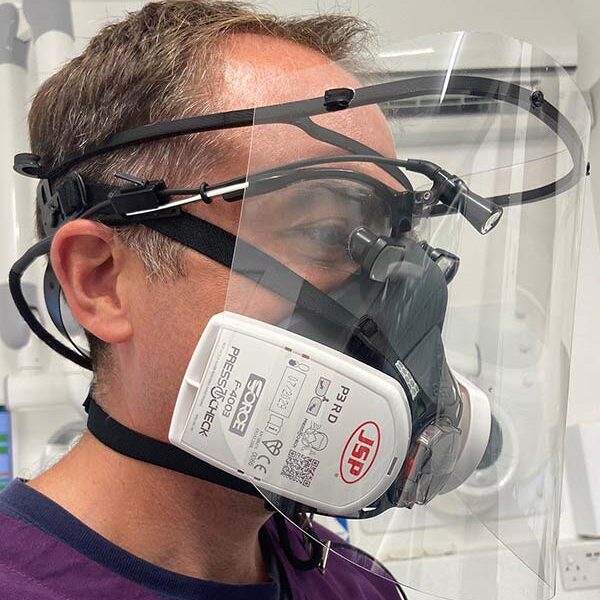 Dentist wearing ukloupes visor over loupes, mask and light